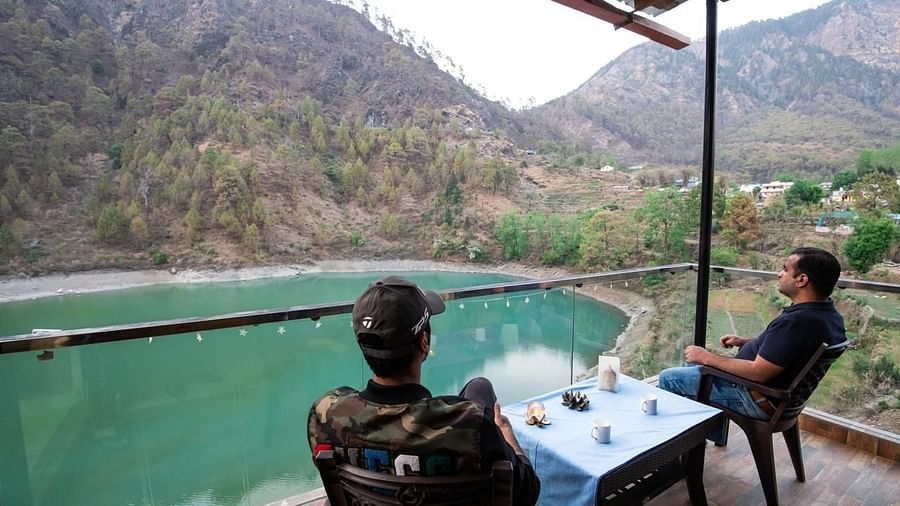 Two people seated at a table on a balcony with a scenic lake and mountain view.
