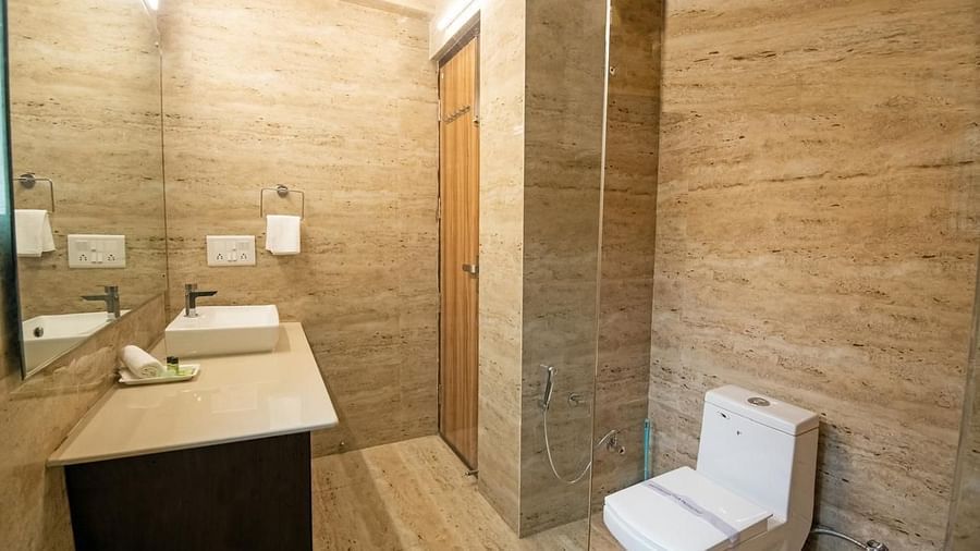 Modern bathroom featuring a square basin on a dark wood vanity, a toilet, and light beige tiled walls.