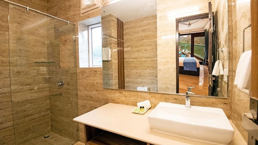 Spacious bathroom with a contemporary white basin, a large mirror, a toilet, and a glass shower enclosure.