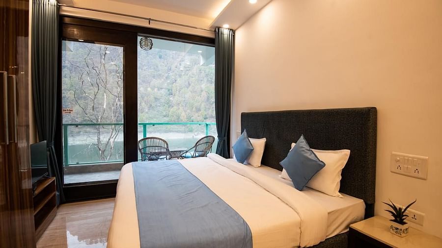 A compact bedroom with a bed placed against the wall, a ceiling fan, and a view through large windows.