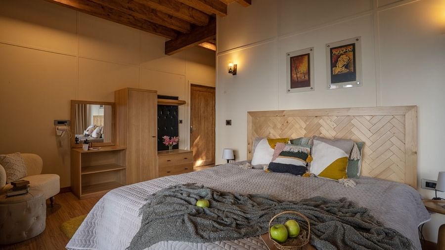 An image of a bedroom with king size bed, frames on the wall, a dressing table, a cabinet at Avalon Cottages, Kanatal