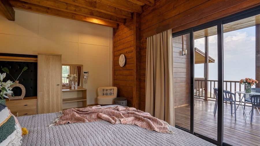 An image of a bedroom with king size bed, frames on the wall, a dressing table, a cabinet at Avalon Cottages, Kanatal