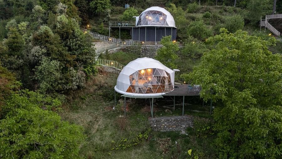 An image of two dome style separate bedroom and a pathway leading to one another amidst a lush garden