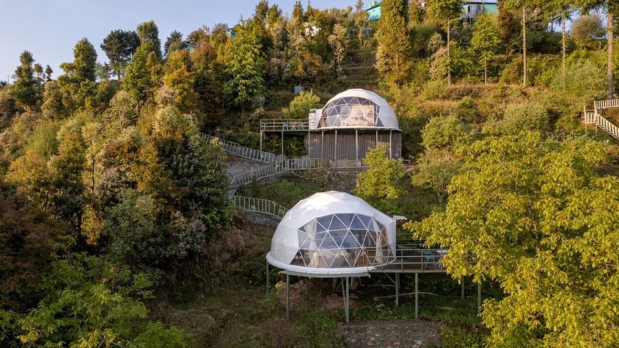 An image of two dome style separate bedroom and a pathway leading to one another amidst a lush garden