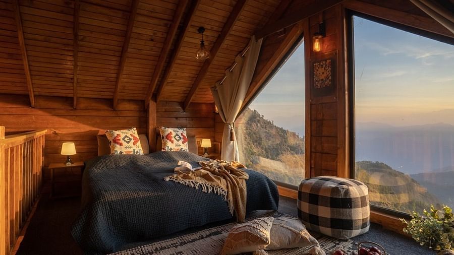 An image of a attic room with king size bed with a huge window providing a view of mountains - Avalon Cottages, Kanatal