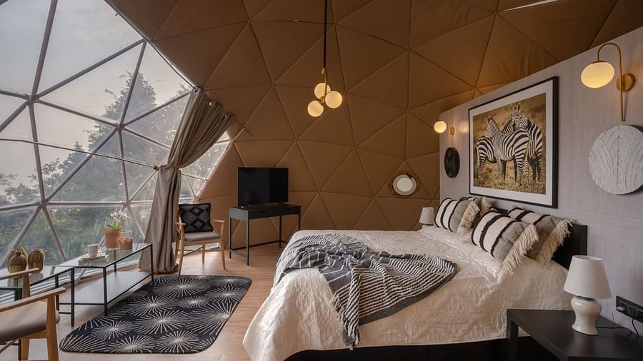 An image of a bedroom in dome cottage with king size bed, bedside table, flat TV screen, chandeliers, etc. | Avalon Cottages, Kanatal
