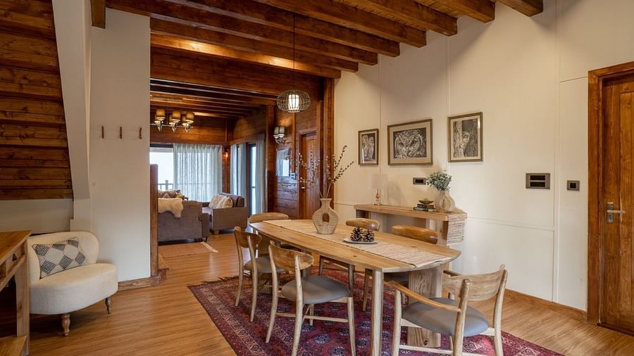 An image of dining space with table and chairs and stairs leading to the attic - Avalon Cottages, Kanatal