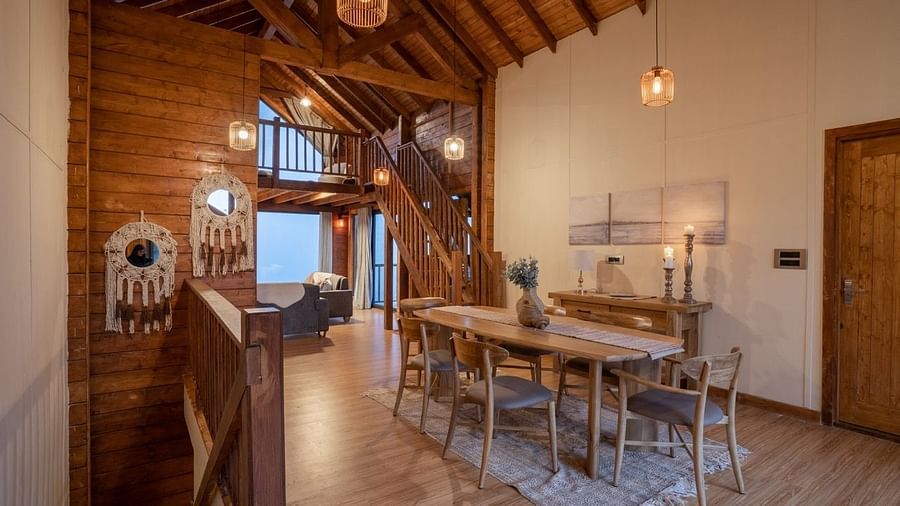 An image of dining space with table and chairs and stairs leading to the attic