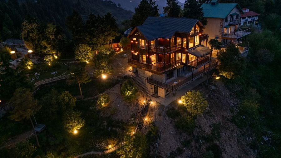 An overview image of of Avalon cottages with lights lit up in the evening with a backdrop of evening sky| Avalon Cottages, Kanatal