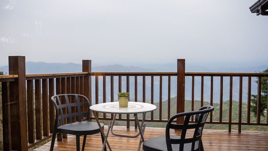 An image of two chairs with a table and a view from the patio | Avalon Cottages, Kanatal