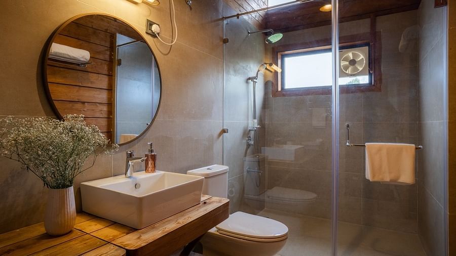 An image of a washroom with sink, faucet, mirror on the wall , shower screen, and a towel hanging inside the shower - Avalon Cottages, Kanatal