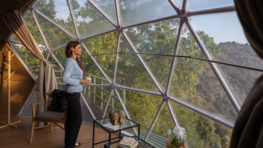 An image of woman enjoying the view from a dome cottage | Avalon Cottages, Kanatal