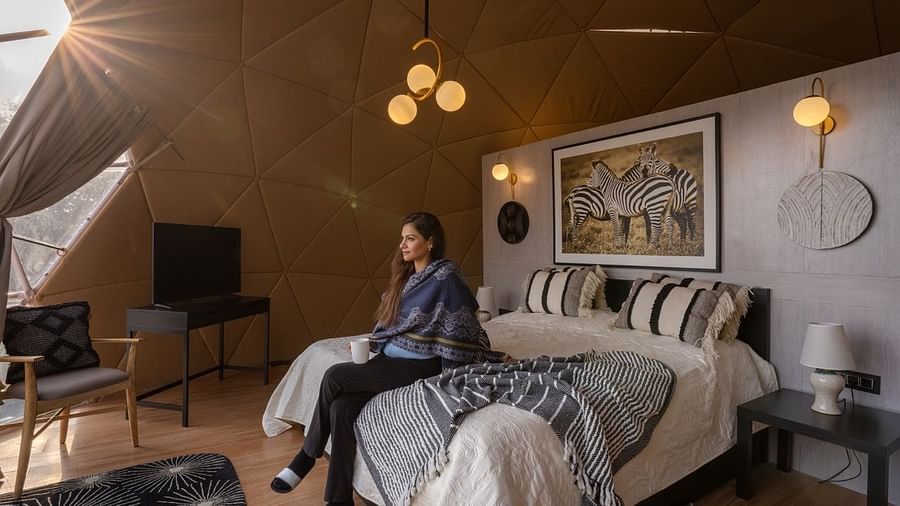 woman inside a room at avalon cottages with a seating and side lamp | Avalon Cottages, Kanatal
