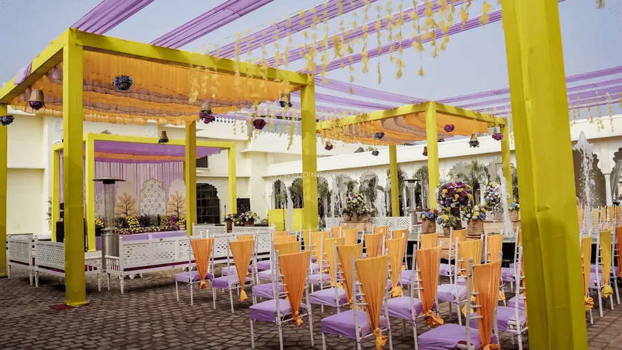Rows of chairs arranged under a yellow and purple canopy structure set for an outdoor event at Beelwa Palace, Jaipur