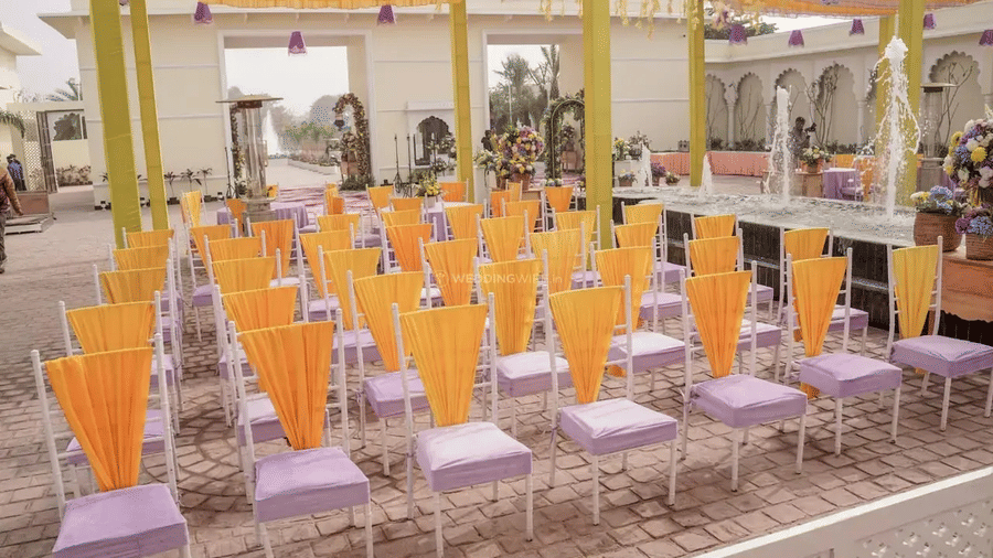 Rows of chairs with yellow coverings arranged in a courtyard with columns at Beelwa Palace, Jaipur.