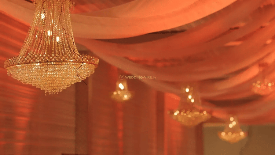 Ceiling with chandeliers and pink drapes hanging over a hall at Beelwa Palace, Jaipur.