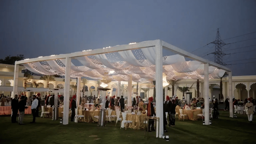 An outdoor event setup at Beelwa Palace, Jaipur, with a large canopy and people gathered for an event.