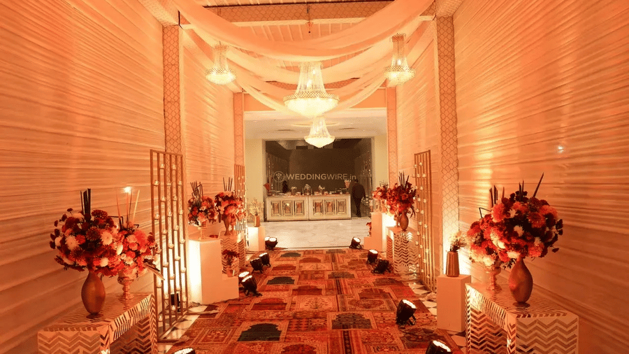 A corridor adorned with drapes and flowers, leading to buffet counter, set up for a destination wedding at Beelwa Palace, Jaipur