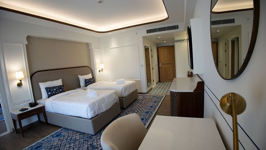 Full view shot of the Triveni Room with modern interiors along with two single beds in the room and bed side tables besides it at Bhagirathi by RDB Atishay.