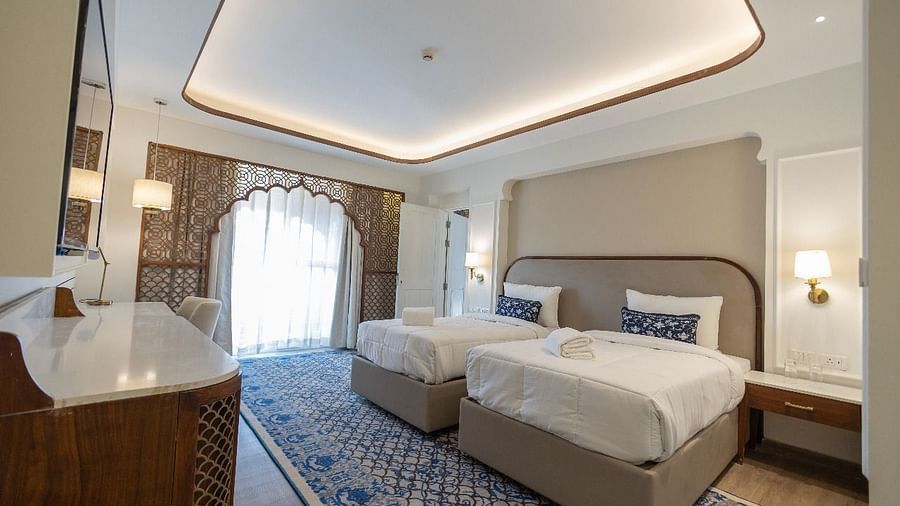 Full view image of the Jalrupa Room with a twin bed with ample of natural light coming from the balcony covered with linen curtains at Bhagirathi by RDB Atishay.