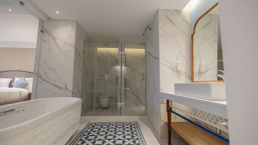 A brightly lit bathroom featuring a bathtub and a well stocked vanity area of the Purna Room at Bhagirathi by RDB Atishay.