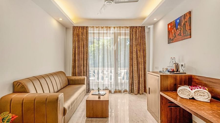 Image of the seating area at Grand Room with a sofas and table with a large window on the side at Calux Joia Do Mar Resort, Goa.