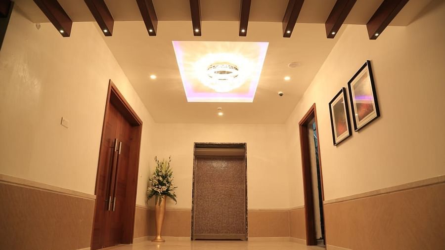 Overview of Orchid Hall at Dhanalakshmi Srinivasan Hotels, Perambalur with paintings on a wall and a plant.