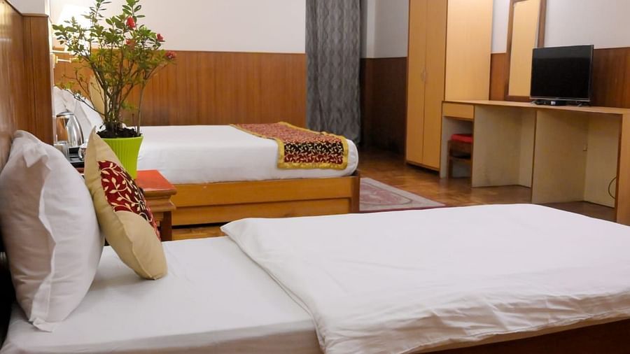 An image of a deluxe room featuring two beds, bed side table, indoor plants, wardrobe, flat screen TV - Sumitel Chiminda, Pelling