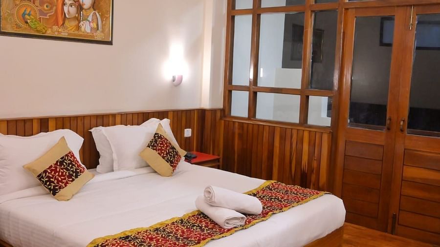 An image of the super deluxe room featuring a queen size bed, bed side table, lamps, and an expansive door leading to the balcony - Sumitel Chiminda, Pelling