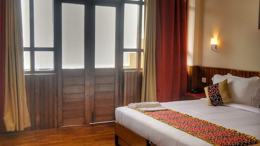 An image of the super deluxe room at Sumitel Chiminda, Pelling featuring a queen size bed, and an expansive door leading to the balcony