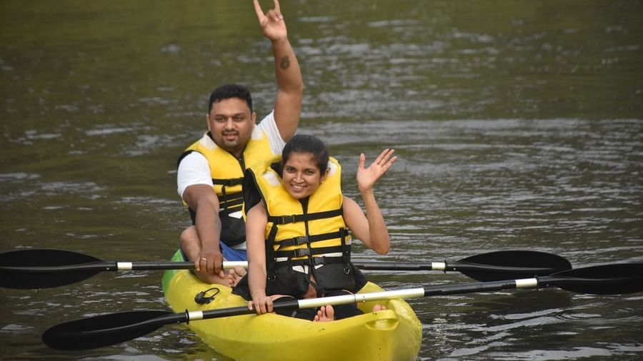 Couple kayaking on a river, joyfully waving at the camera - Evergreen County