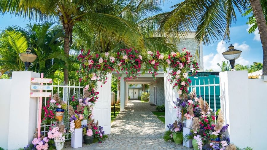 An elegant outdoor archway decorated with purple and white flowers, leading into a light-colored building | Grande Pavillion | Grand Bay Resort and Spa