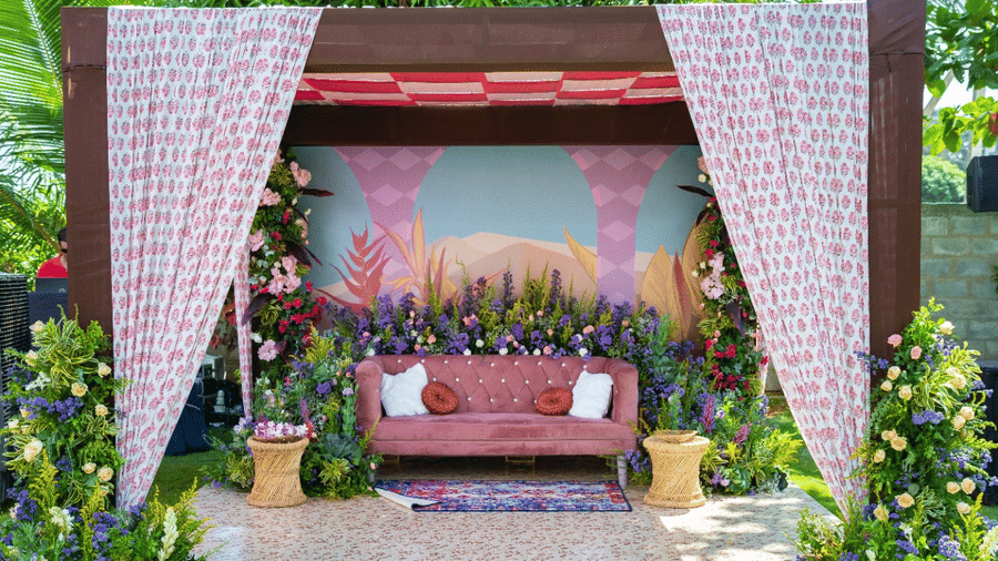 An outdoor wedding stage or mandap with a pink and white floral and fabric theme, featuring a seating area, set on a green lawn - Grande Bay Resort & Spa, Mamallapuram
