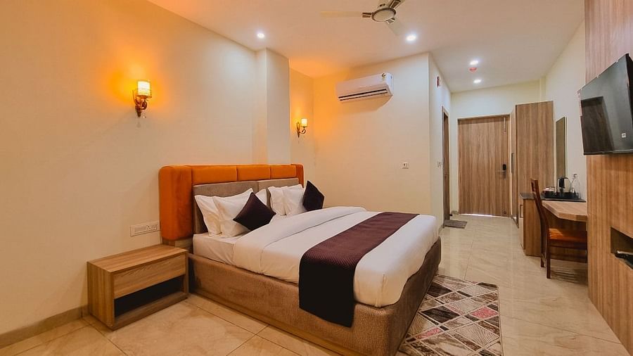 Deluxe Room with bed, rug by the foot of the bed, and television on the wall  at Pines and Peaks, Dalhousie 