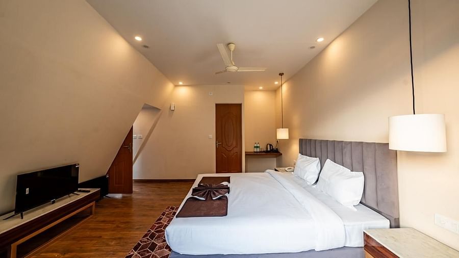 A hotel bedroom with a large white bed, a TV, and a ceiling fan