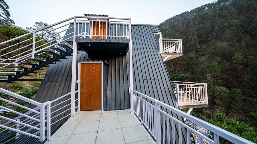 An outdoor metal staircase with white railings leading up a steep hillside towards a building, under a clear sky.