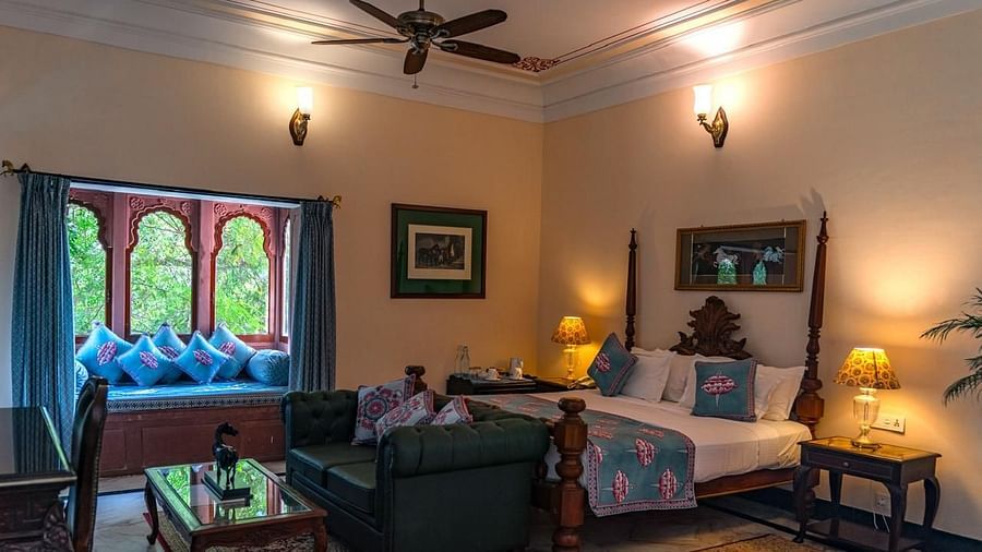 Deluxe Room Featuring a four-poster bed, a window seating area with decorative cushions, and elegant decor - Khas Bagh, Jaipur
