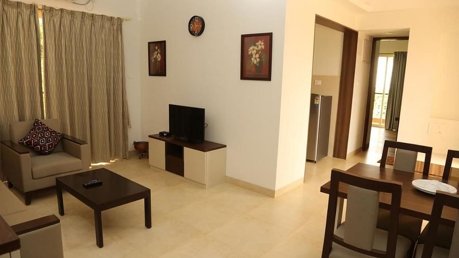 Diagonal view of a room with curtained windows, two doorways leading to different rooms, and a dining table with chairs arranged at La Vida Studio Inn.