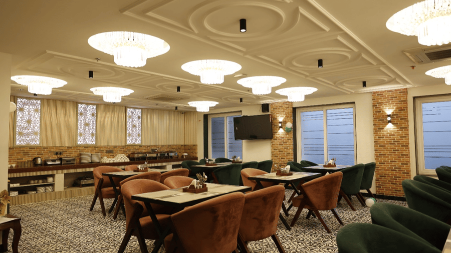 Banquet hall of Lime Tree Hotels & Service Apartment Private Limited featuring chandeliers, dining tables, and ornate ceiling decor.