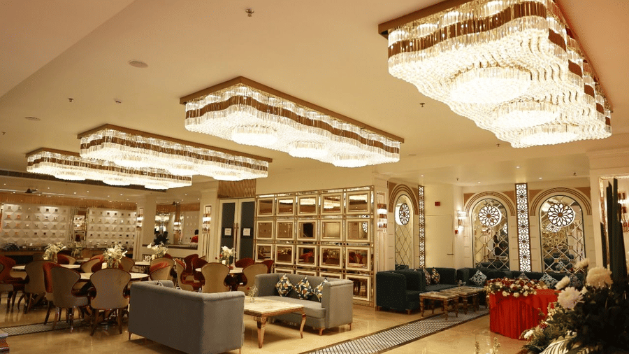 Lounge area of Lime Tree Hotels & Service Apartment Private Limited featuring crystal chandeliers, sofas, and marble flooring.
