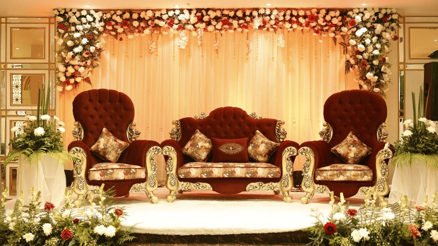 Wedding stage setup at Lime Tree Hotels & Service Apartment Private Limited featuring ornate throne chairs and floral decorations.