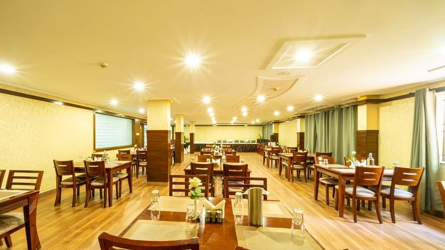A well lit dining hall with wooden tables and chairs awaits guests, ready for meals at Lords Midtown Suites.