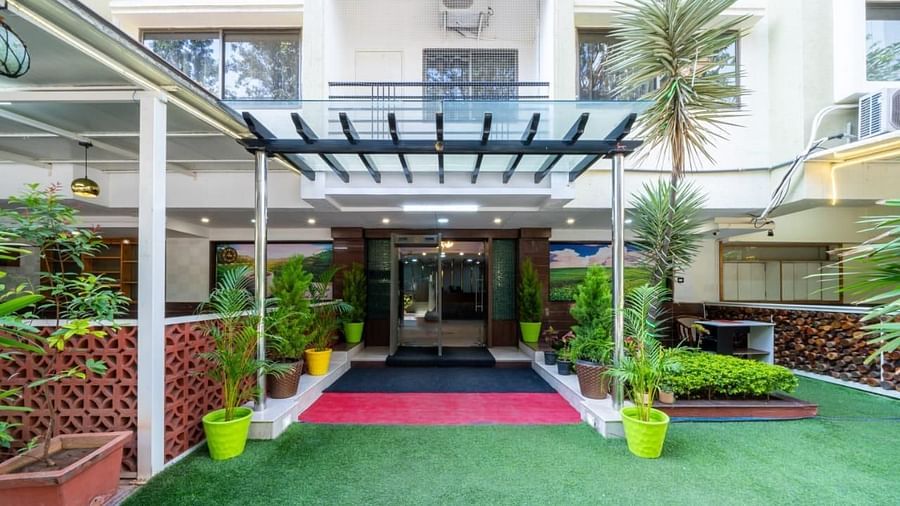 The hotel entrance features lush greenery and a welcoming pathway leading to the reception at Lords Midtown Suites.