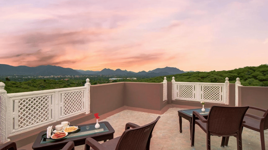 The rooftop terrace at Mewar Mansion Villa By Amantra, Udaipur boasts seating with sweeping, colorful sunset views.