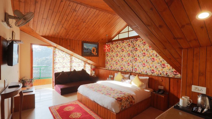 A cottage-styled bedroom with wooden ceiling and glass windows at Mongas Hotel & Resort, Dalhousie.