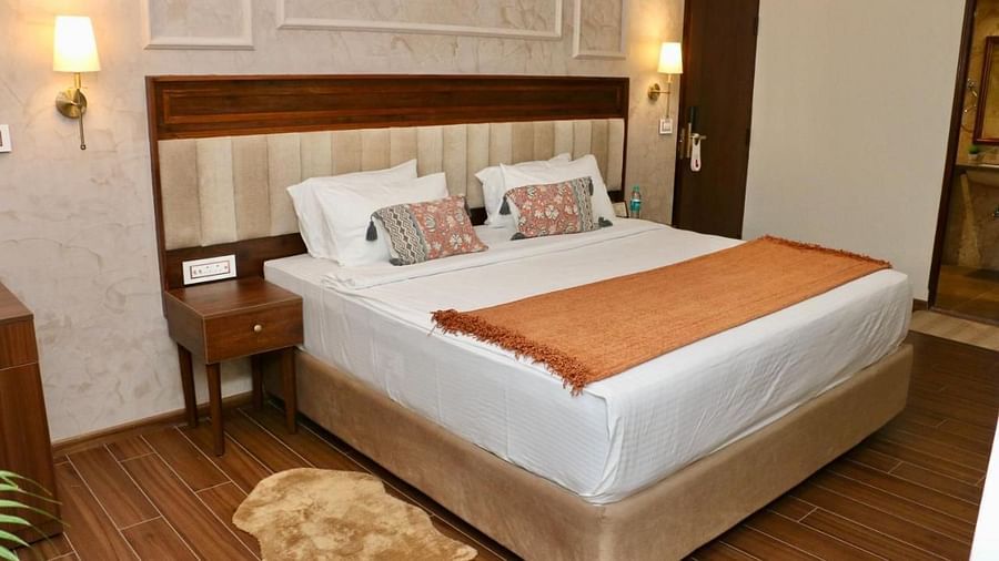 A neatly made bed with white linens and decorative pillows of Luxury Junior Suite at Nalapad Hotel Bangalore International.