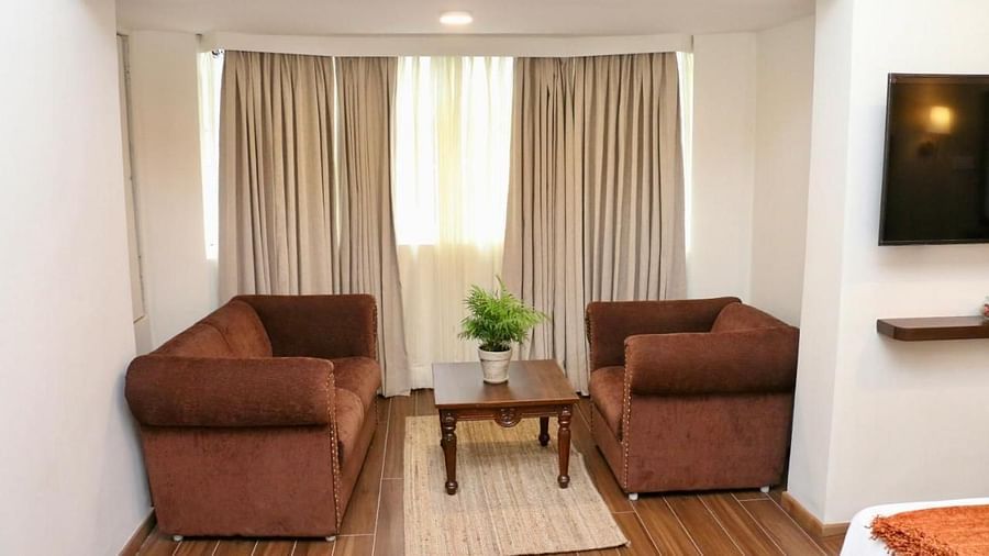 A living room of a Luxury Junior Suite with armchairs, a table, and neutral decor. - Nalapad Hotel Bangalore