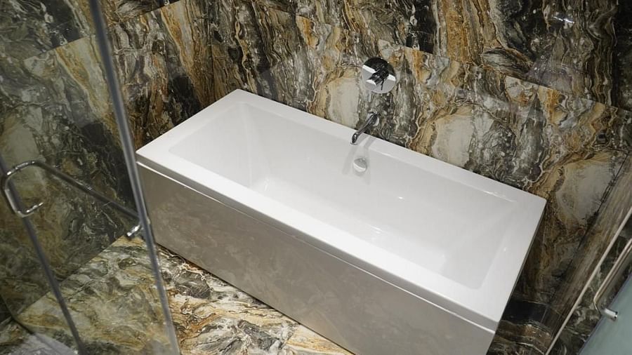 A rectangular, white bathroom sink is featured against a textured, earth-toned wall in Royal Heritage Suite at Nalapad Hotel Bangalore International