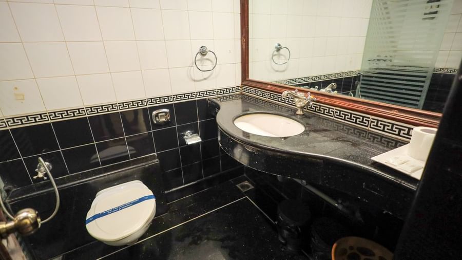 Bathroom with black tiled walls, large mirror, countertop basin, and white toilet at Paradise Isle Beach Resort.
