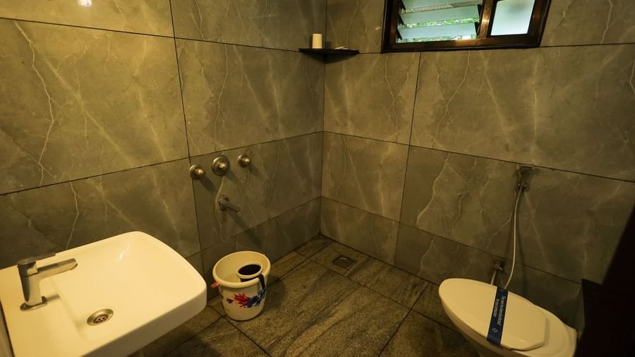 Simple bathroom with grey tiled walls, white toilet, and floor-mounted shower at Paradise Isle Beach Resort.